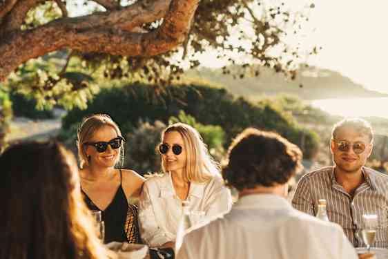 Group of people at table with food under trees