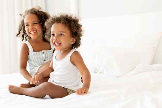 Two children sitting on a bed