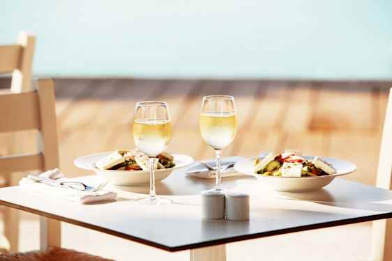 Food and wineglasses on table by a pool