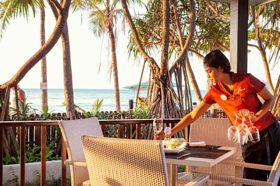 Woman setting up table at beach restaurant