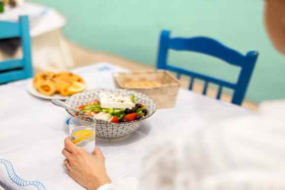 Wineglass and greek salad on table by the sea