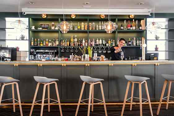 Bartender pouring a drink in green bar