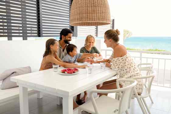 Family eating melon at table on balcony