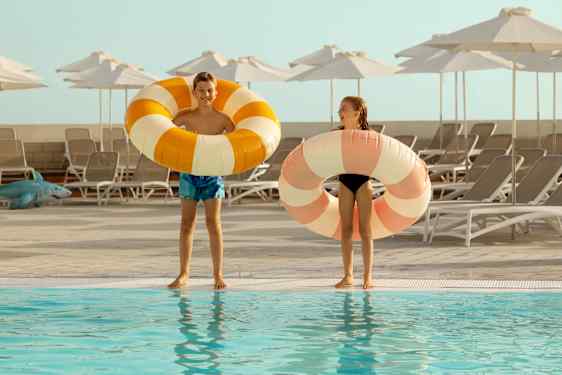 Girl and boy with striped bathrings by poolside
