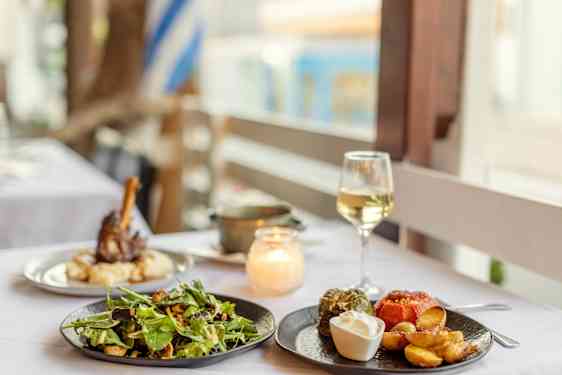 Wineglass and greek salad on table by the sea