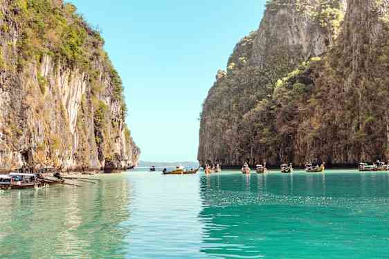 Longtailboats at sea between rocks