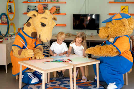 Lollo & Bernie sits at a table and crafting with two kids