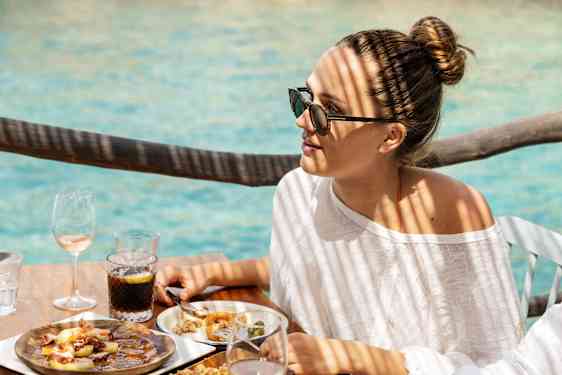 Woman eating at table by the sea