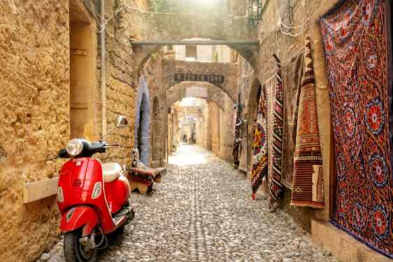 Red vespa in alley and carpets on wall