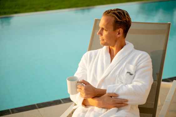 Woman drinking coffee by the pool