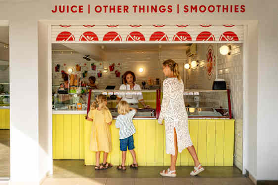 two kids and woman at yellow juice bar counter