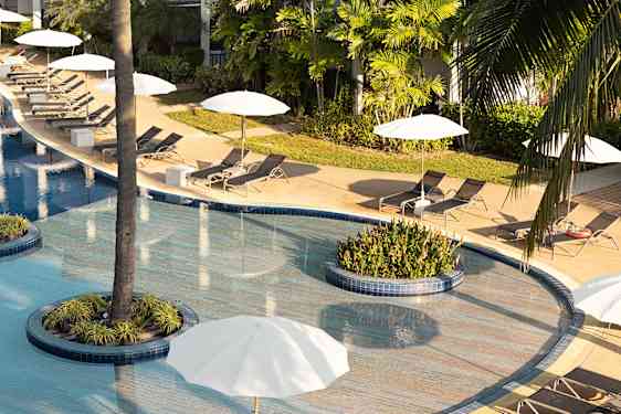 Poolarea with sunchairs and white umbrellas