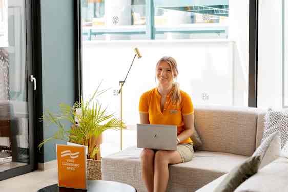 Staff sits on sofa with laptop in knee
