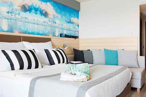 Ljust hotellrum med dubbelsäng och soffa på Sunprime C-lounge