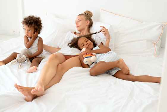 Mom and two daughters relaxing on bed
