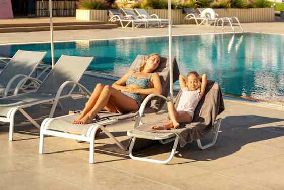 Woman and girl relaxing on sunbeds by the pool