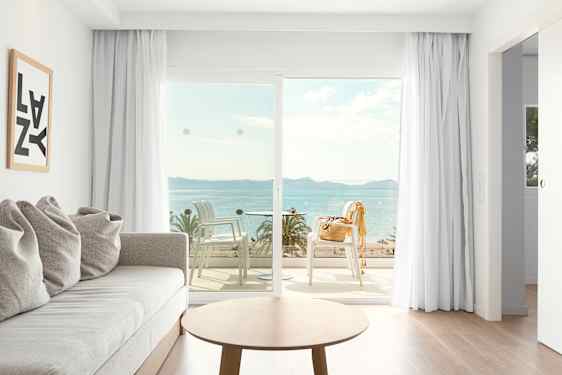 Ljust hotellrum med soffa och soffbord och utsikt över strand och hav
